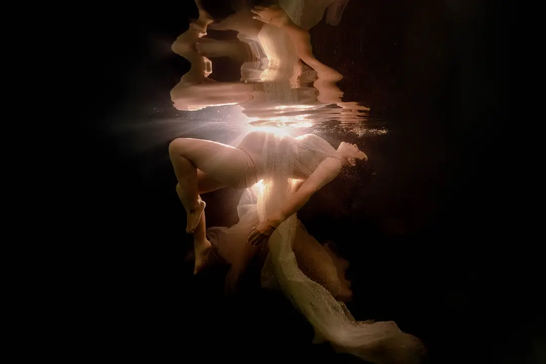 Femme enceinte sous l’eau avec des rayons de lumière en piscine à Marseille