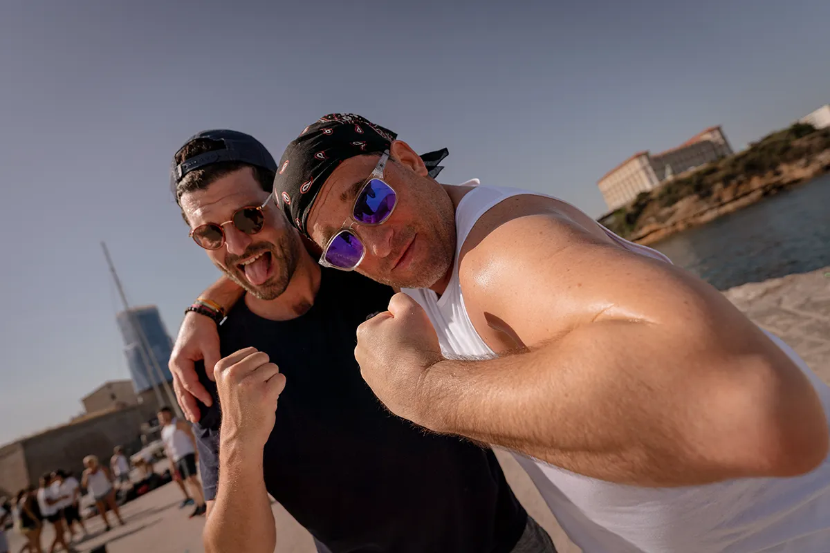 Deux collaborateurs rigolant et montrant leurs muscles après un effort, ambiance détendue lors d'un séminaire entreprise à Marseille.