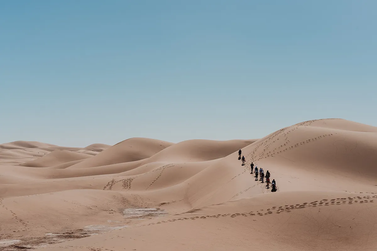 Groupe en marche dans les dunes pendant une retraite yoga au Maroc