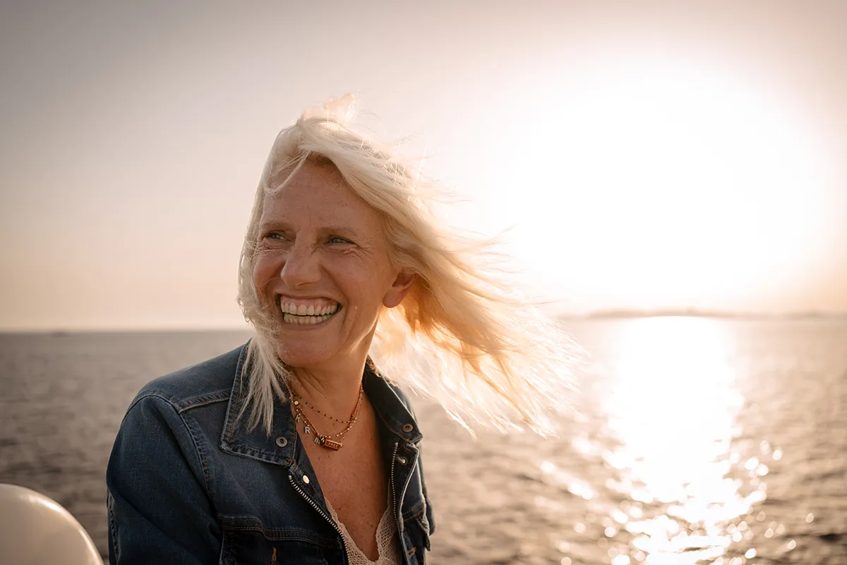 Portrait spontané d'une collaboratrice souriante au coucher du soleil lors d'un séminaire d'entreprise à Marseille sur un bateau.