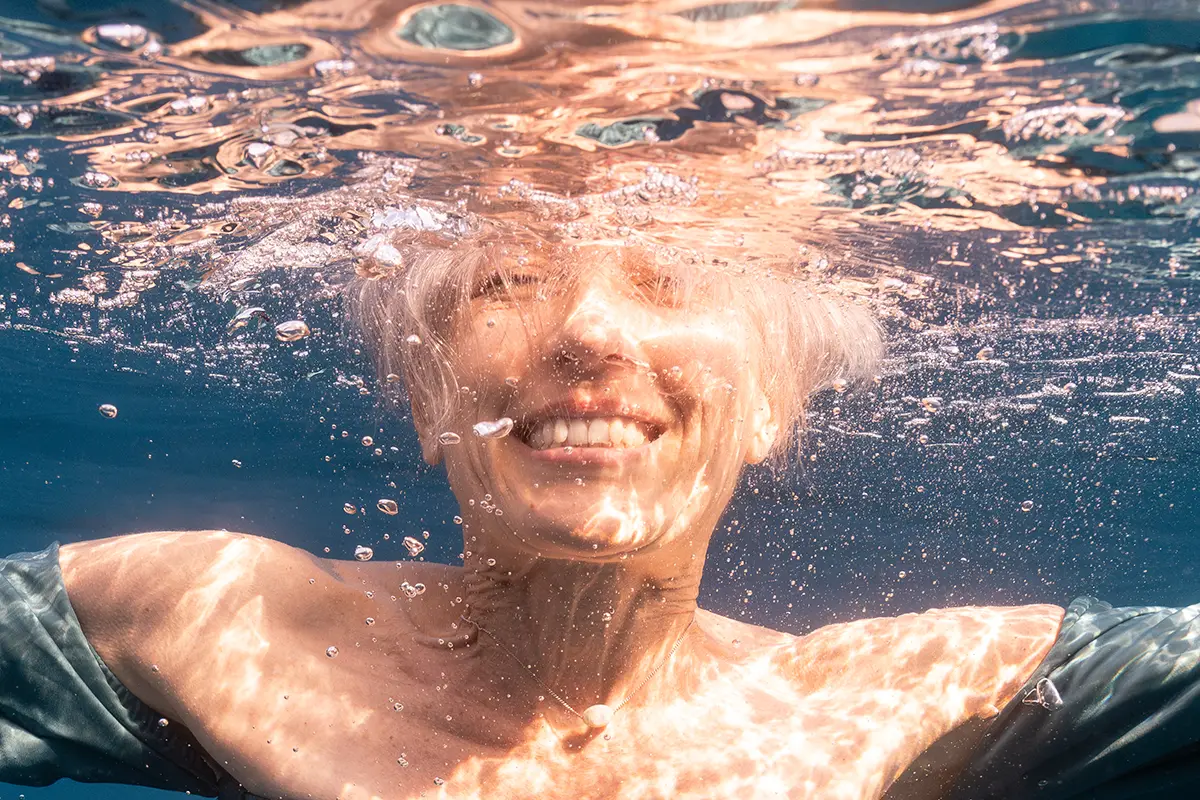 Portrait d'une femme souriante en apnée lors d'une séance photo aquatique à Marseille.