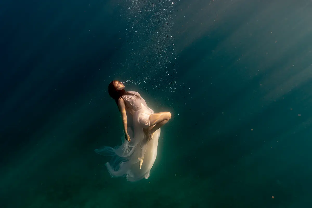 Tissu fluide se déployant sous l'eau lors d'une séance de photographie aquatique artistique.