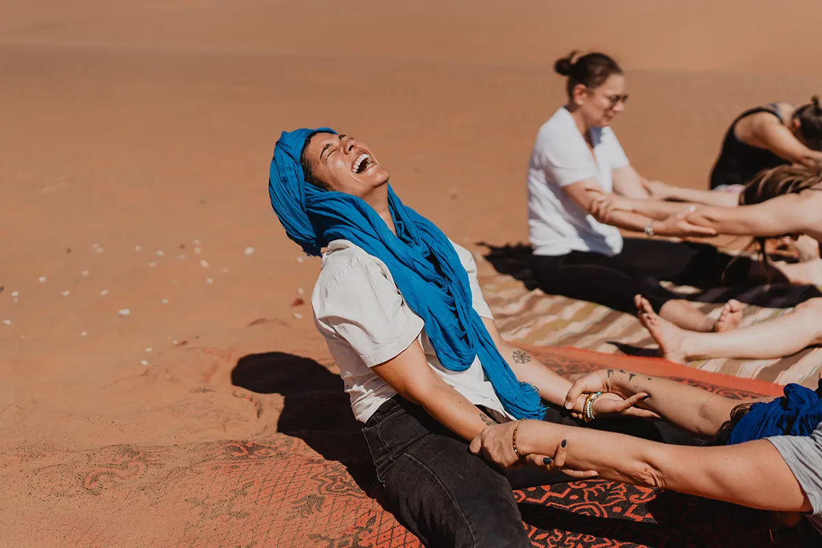 Femme souriante pendant une séance de yoga dans le désert marocain