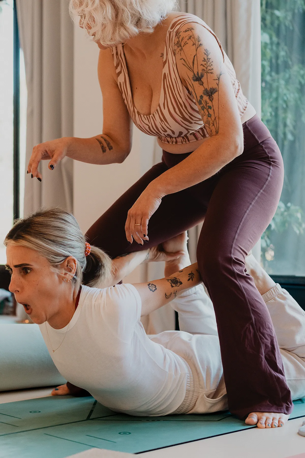 Ajustement physique bienveillant par une professeure lors d'un cours, séance photo pour un studio de yoga à Aix.