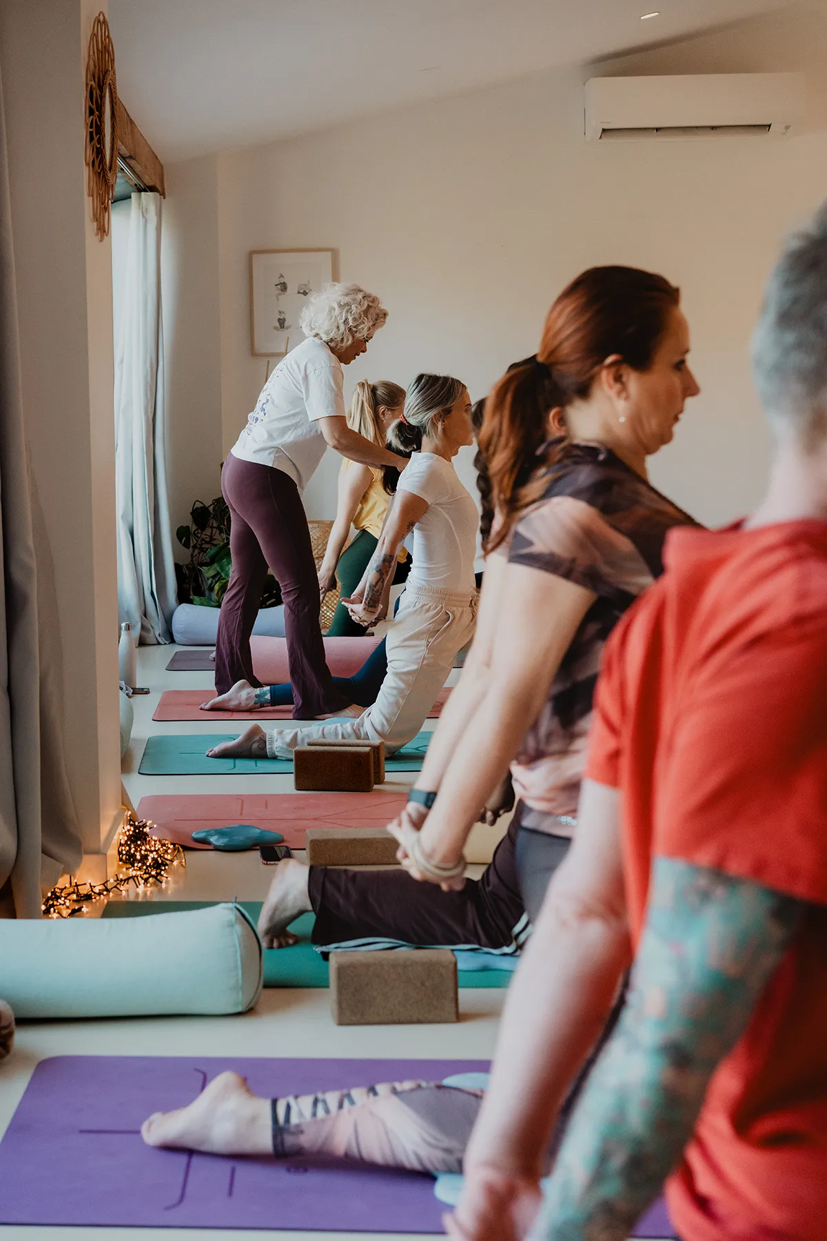 Correction de posture pendant un cours de yoga, shooting photo réalisé par un photographe studio yoga Aix-en-Provence.