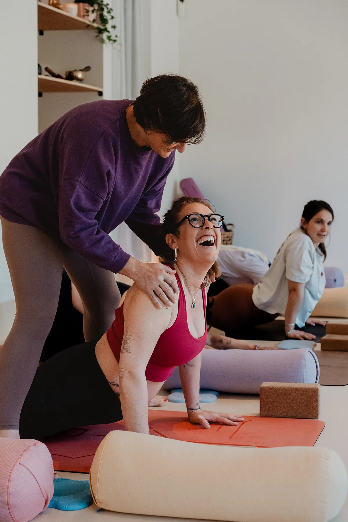 Moment d'échange bienveillant et ajustement de posture entre une professeure et une élève lors d'un cours, reportage par un photographe studio yoga Aix-en-Provence.