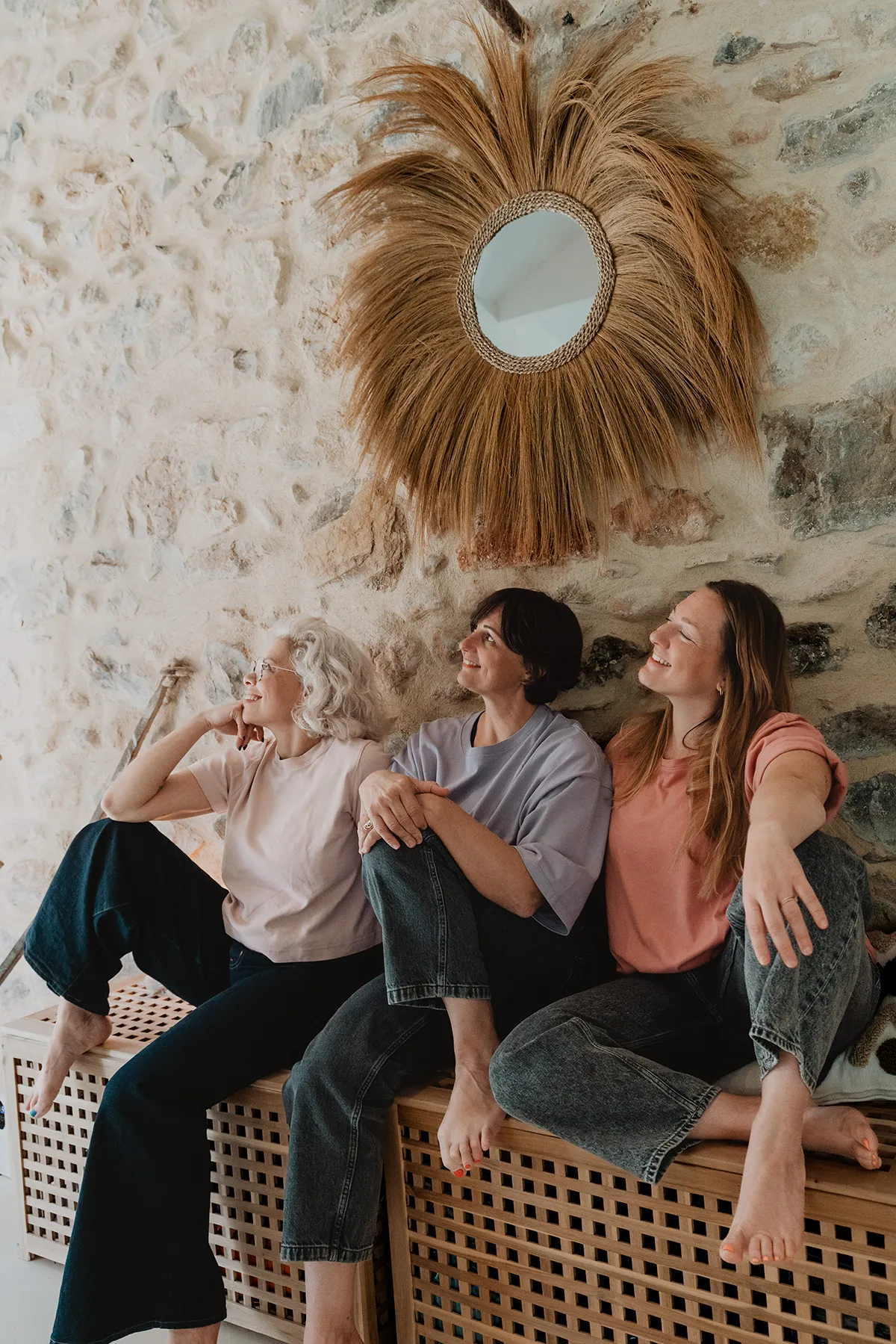 Trois professeures détendues assises contre un mur en pierre, intérieur studio yoga Aix-en-Provence, ambiance chaleureuse.