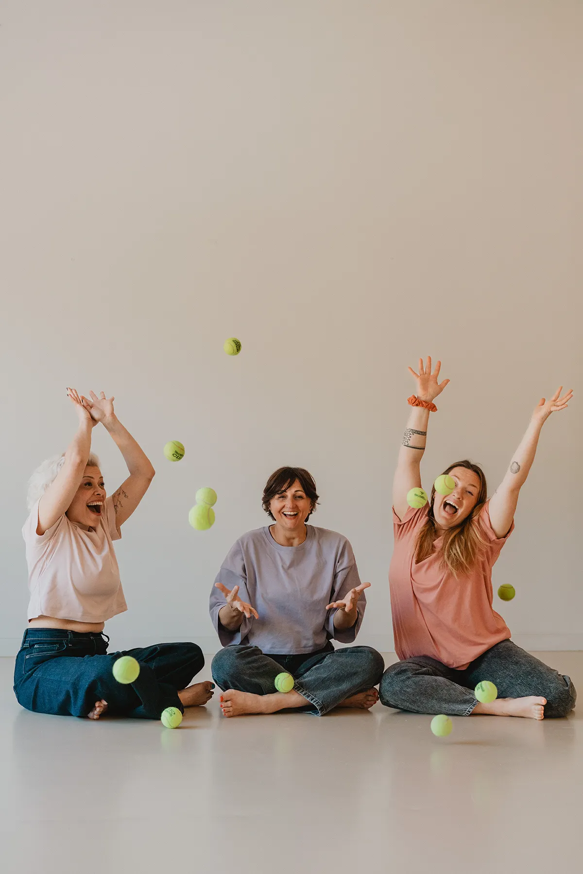 Femmes lançant des balles de tennis en l'air en riant, séance photo décalée avec un photographe studio yoga Aix-en-Provence.