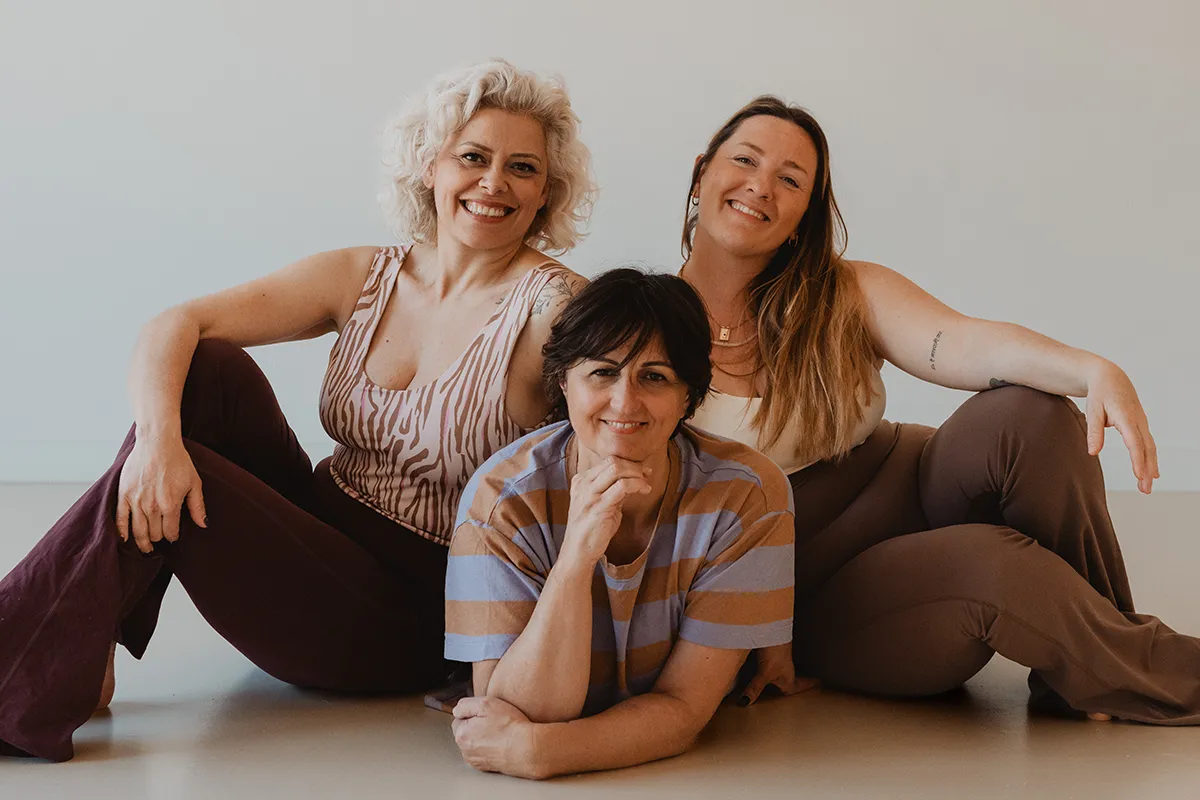 Trois femmes assises au sol en tenue décontractée, complicité entre professeures, shooting photo studio yoga Aix-en-Provence.