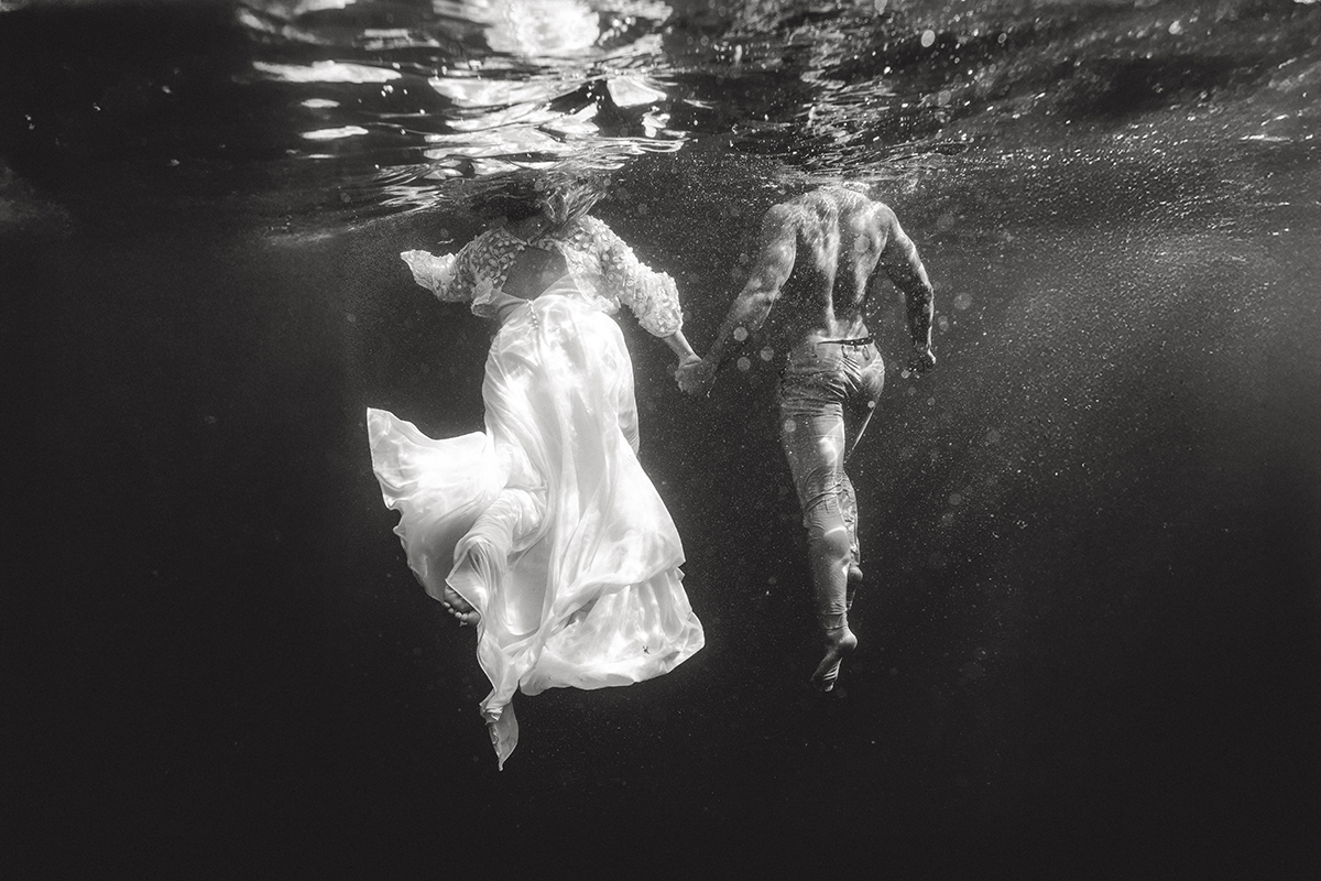 Couple en immersion progressive lors d'une séance photo mariage sous l'eau aux Calanques de Marseille.