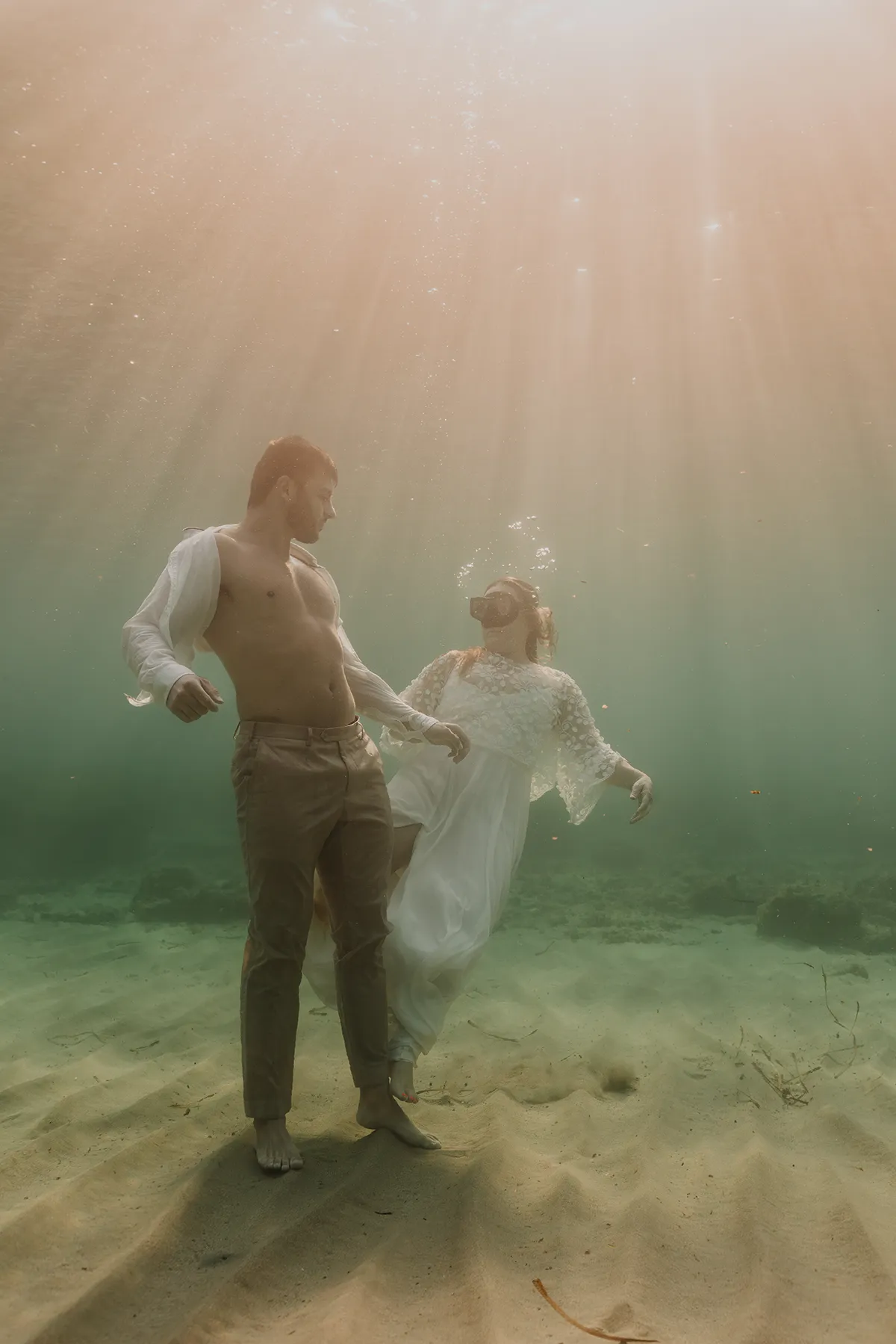 Couple de mariés en immersion totale, photographe mariage sous-marin Marseille, lumière naturelle