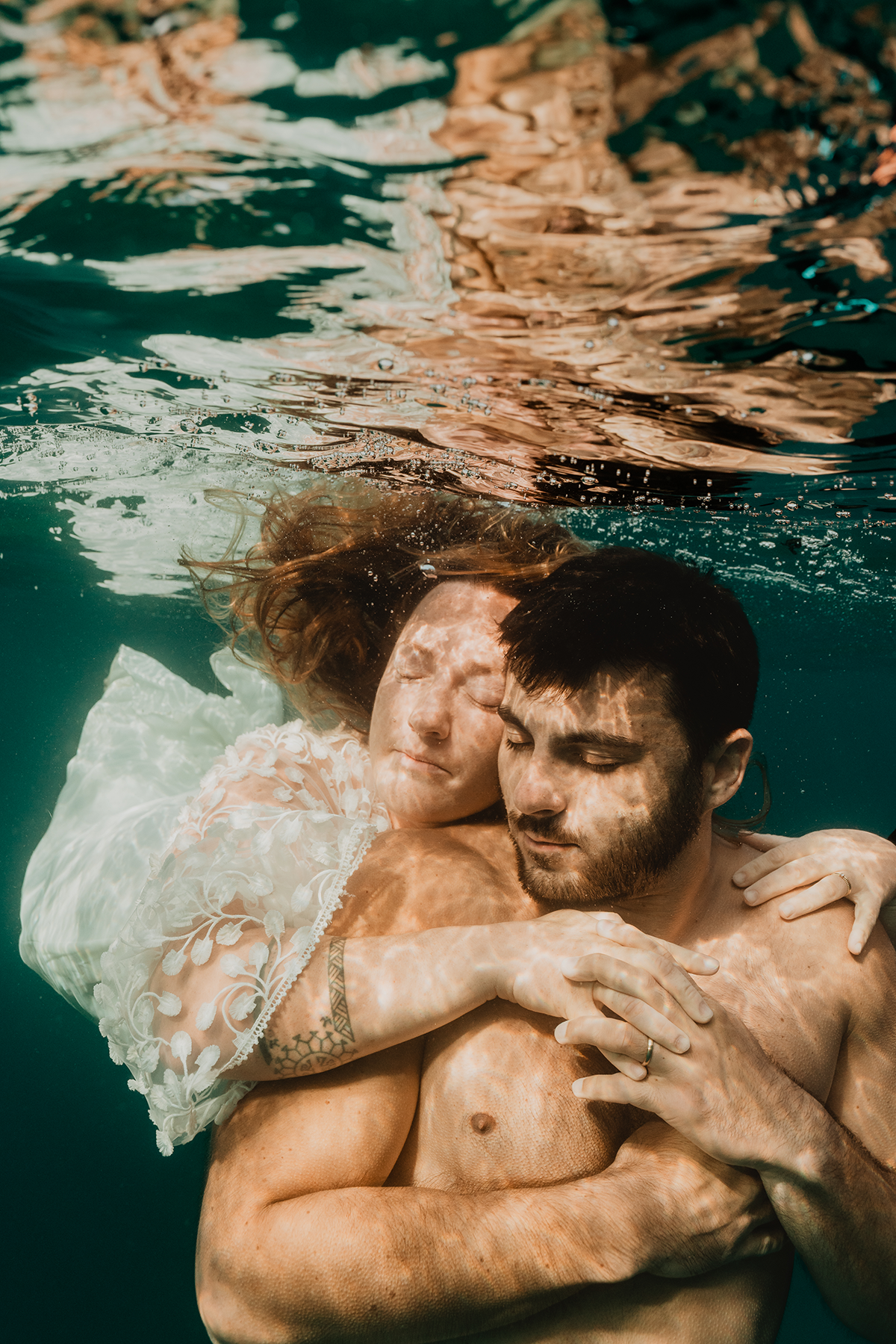 Portrait sous-marin émouvant d'un couple de mariés, regards complices lors d'une photo mariage sous l'eau à Marseille.