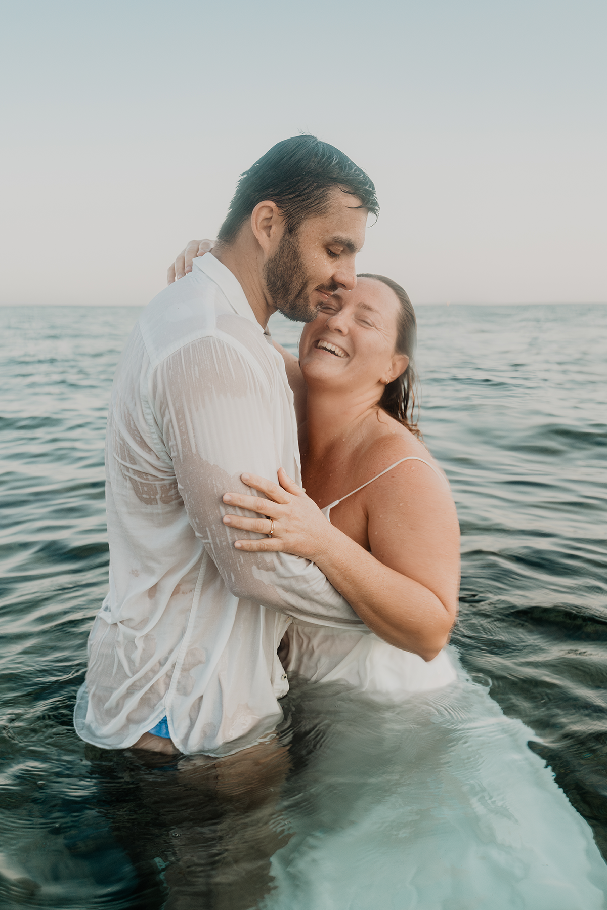 Couple de mariés remontant à la surface souriants après une séance photo sous l'eau aux Calanques de Marseille.