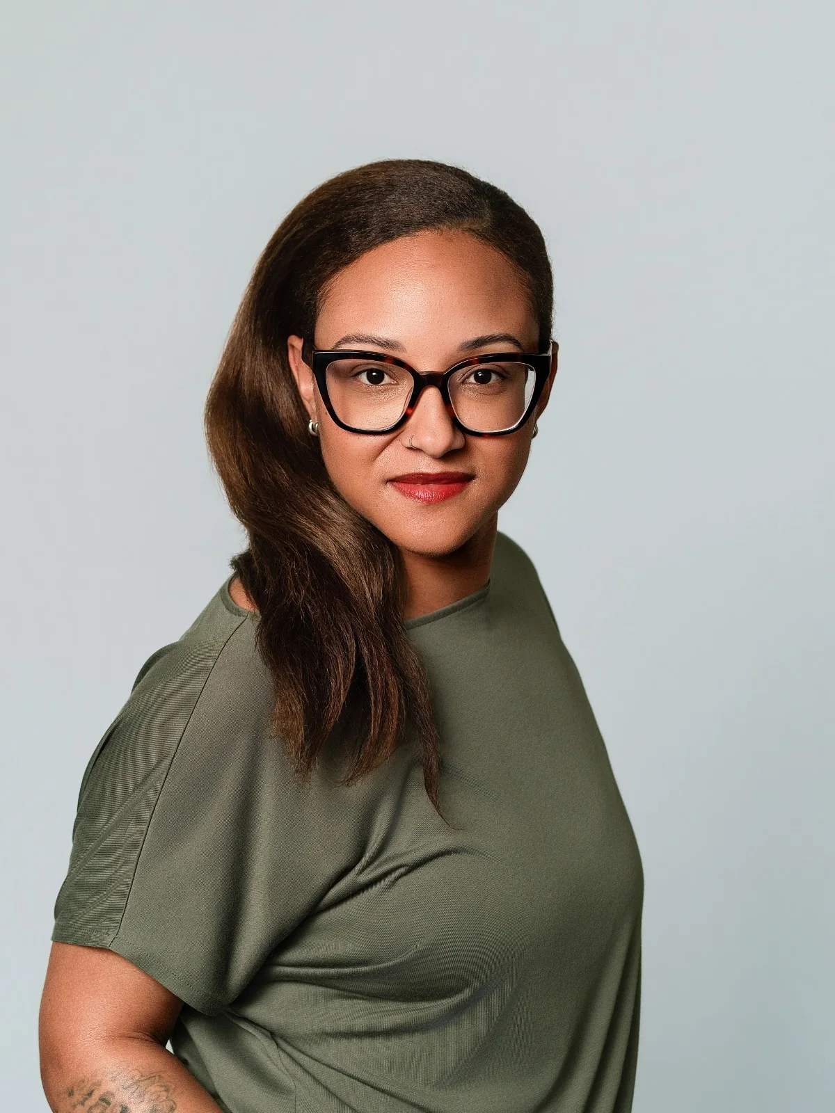 Portrait sur fond gris, avec lunettes et tee-shirt vert kaki.