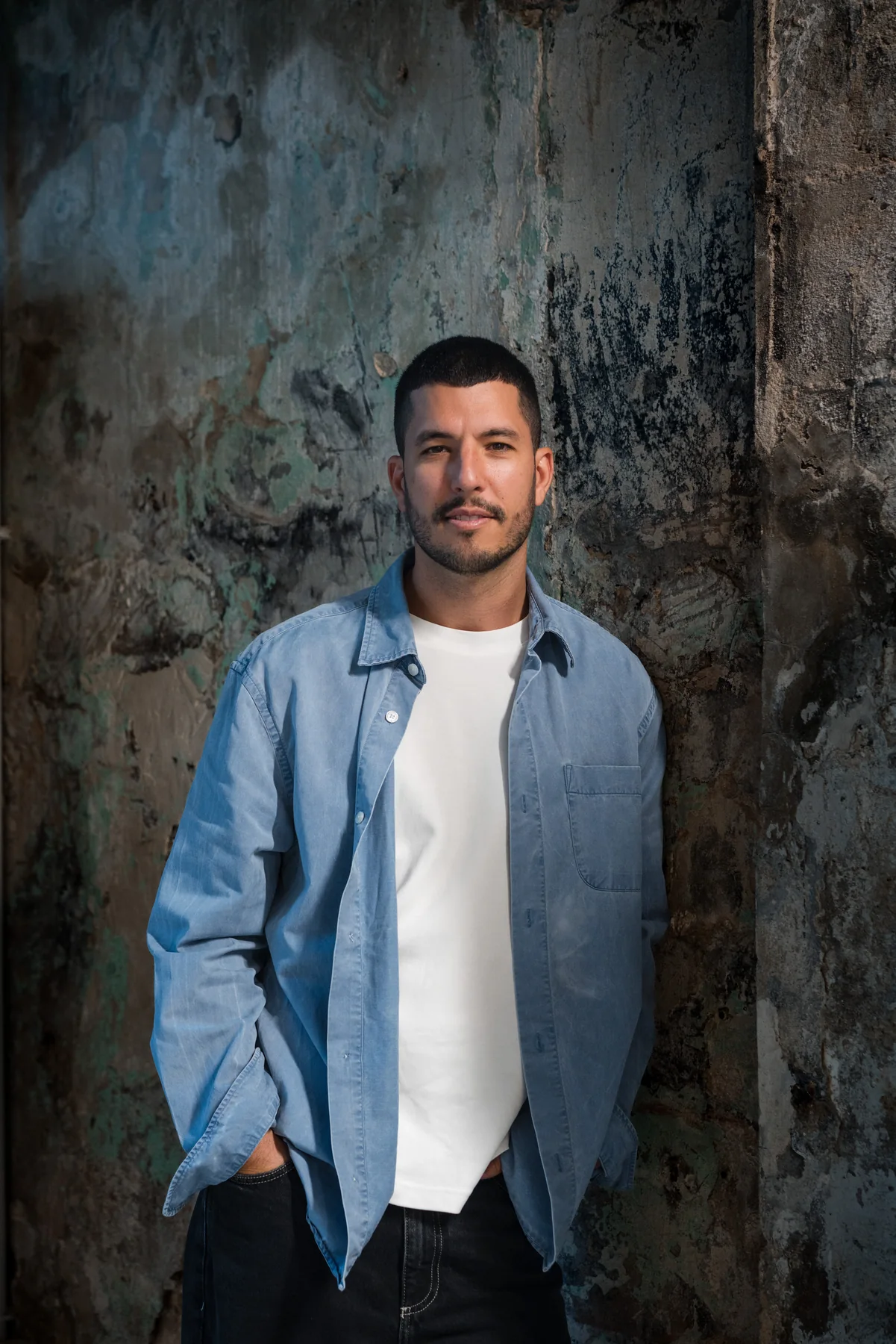 Portrait professionnel à Marseille pour Loris, créateur de Sobre Studio, debout en surchemise bleue devant un mur texturé