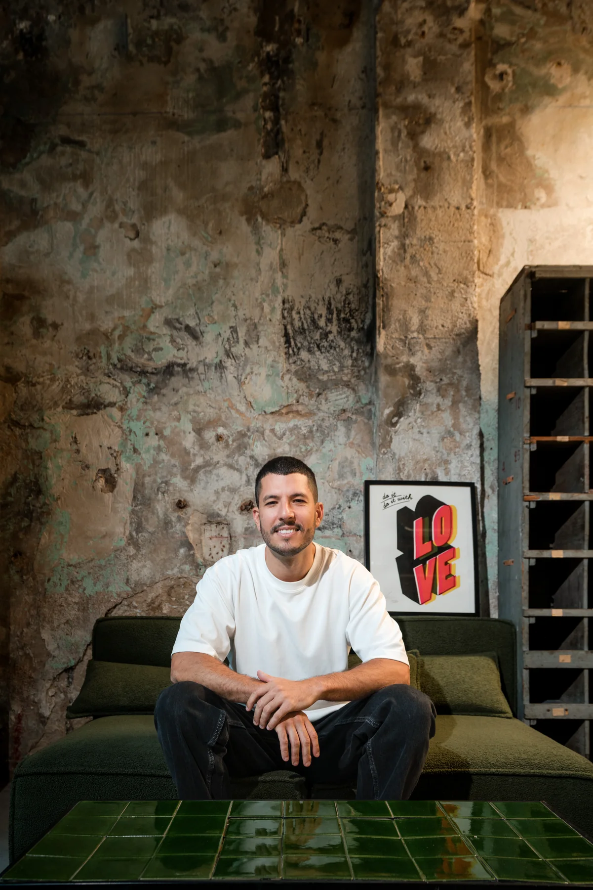 Loris assis sur un canapé vert dans le décor brut du coworking ALT