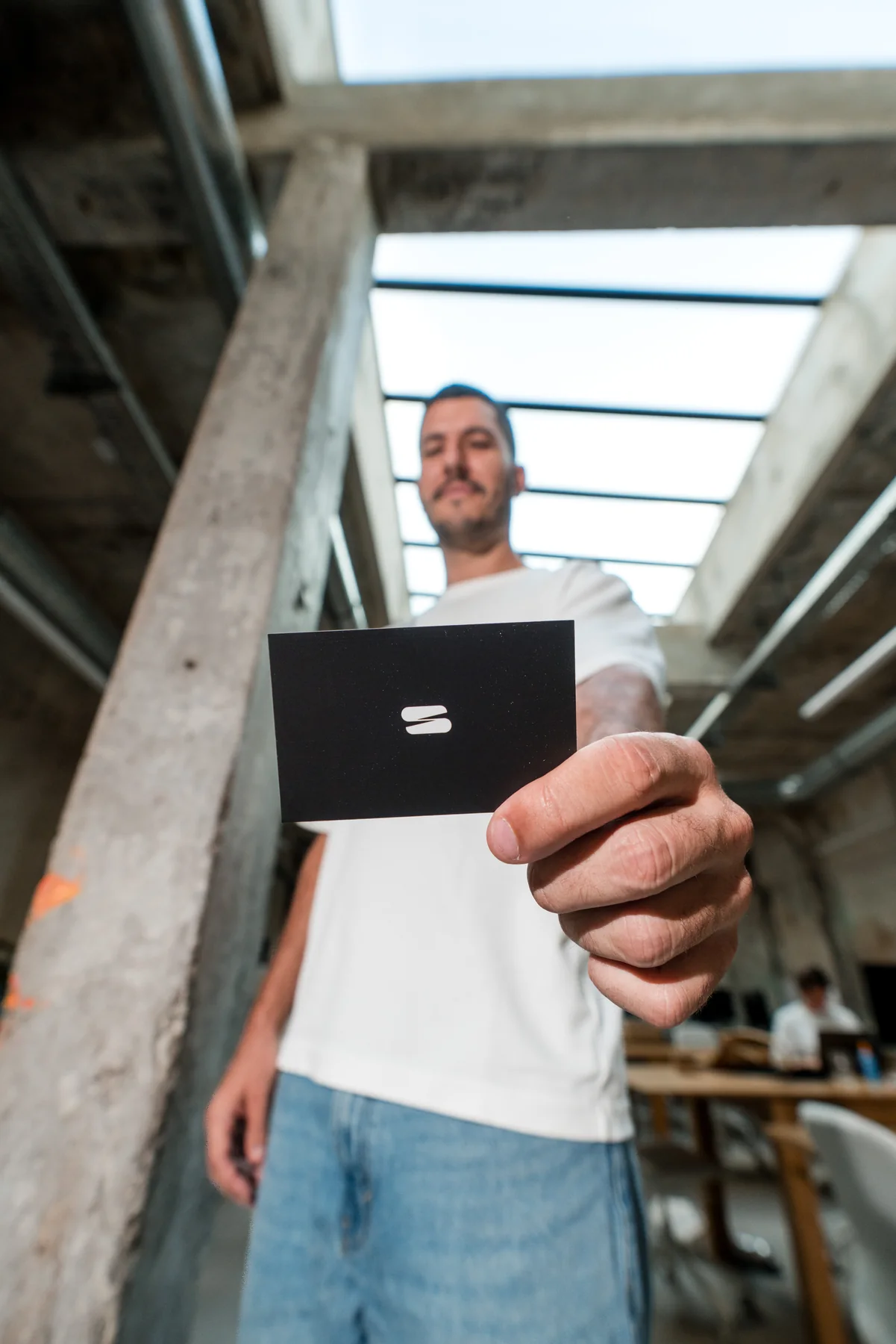 Lors d'une séance photo pour des portraits professionnels à Marseille, Loris tend sa carte de visite au premier plan